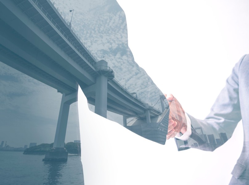 Double exposure of two business persons shaking hands and bridge skyline, relationship conceptual abstract